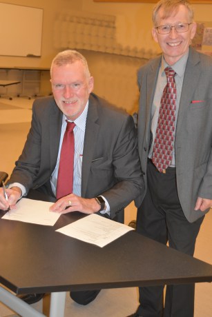 Official Trustee Mike McKay signs paperwork with Interim Secretary-Treasurer Bruce Hunt at his last official Board of Education meeting on Oct. 16, 2018.