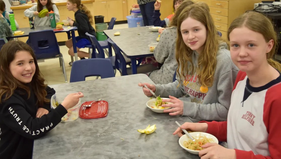 Students eating bowls of noodles, vegetables and chicken. Filip
